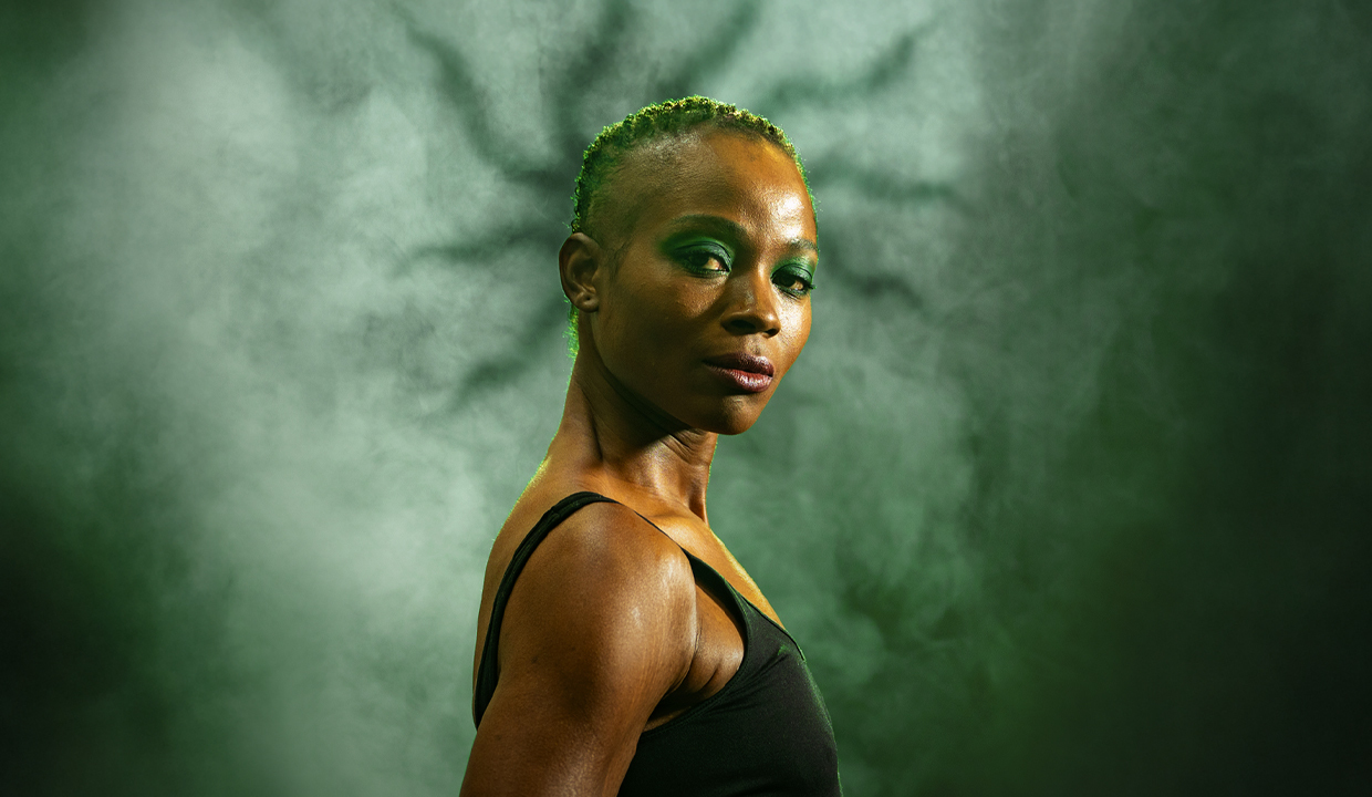 Oyin Oladejo standing in front of a green backdrop. Behind her head is a shadow of snakes.